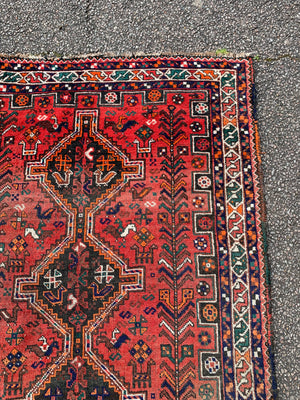 A red ground Persian rectangular rug with animal motifs- 159cm x 112cm