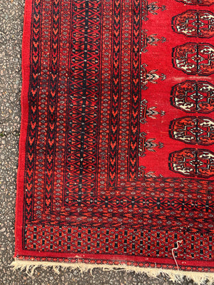 A Persian red ground rectangular Bokhara rug
