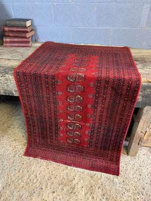 A Persian red ground rectangular Bokhara rug
