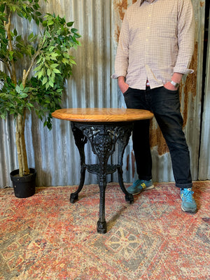 A cast iron Britannia garden table with oak top