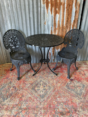 A black cast metal garden table and two chairs