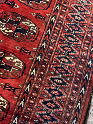 A hand woven Persian red ground rectangular rug with multiple lozenges