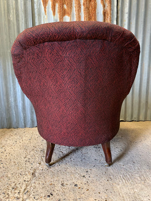 A black and red button back Victorian armchair raised on castors