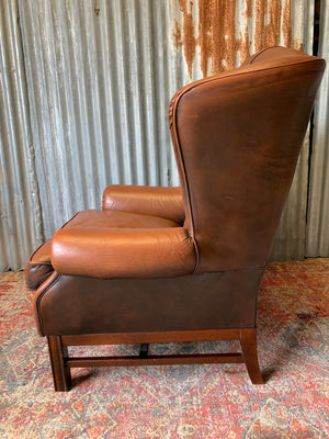 A brown wingback Chesterfield armchair with button back