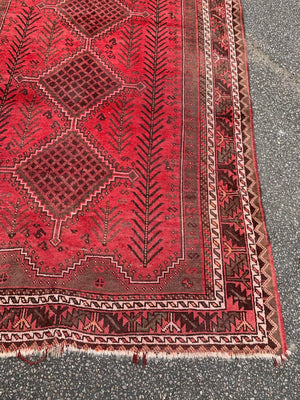 A large hand knotted Persian red ground rectangular rug