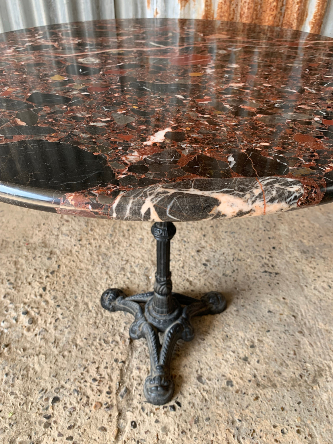 A black cast iron bistro table with red Palladio granite top - large (one available)