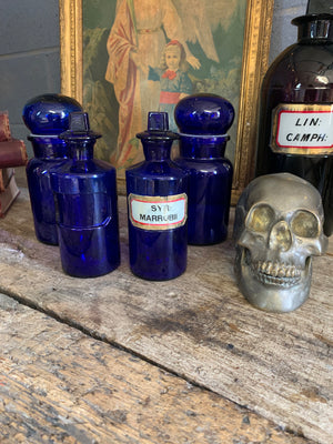 A collection of four cobalt blue glass apothecary bottles