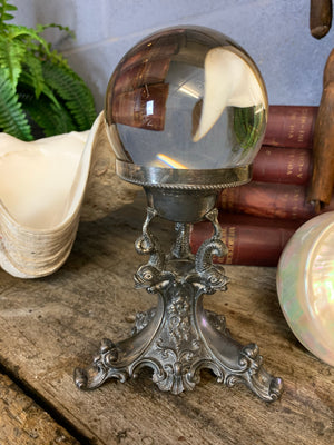 A fortune teller's crystal ball on a silver plated dolphin stand