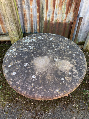 A large round weathered circular stone pedestal table
