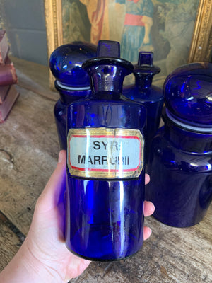 A collection of four cobalt blue glass apothecary bottles