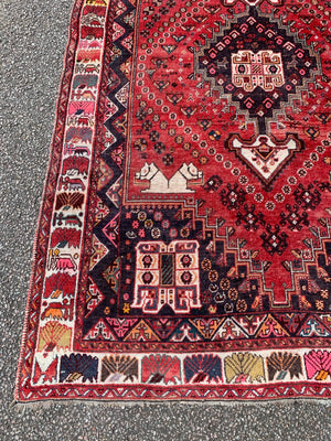 A large red ground rectangular Persian rug with camel motif
