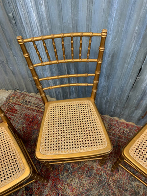 A set of four faux bamboo chairs with cane seats