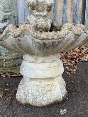 A cast stone bird bath with the figure of a fawn