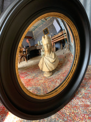 A large black and gold convex mirror