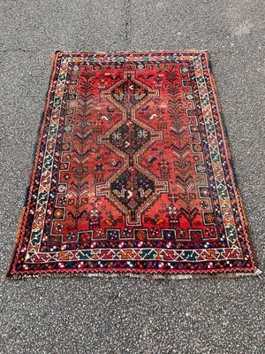 A red ground Persian rectangular rug with animal motifs- 159cm x 112cm
